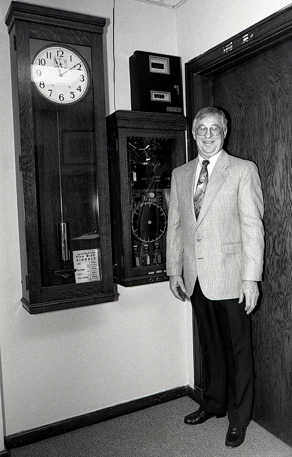 1994 Talco School Superintendent John Gable stands beside the school clock, bell and alarm system that was state of the art in 1939.